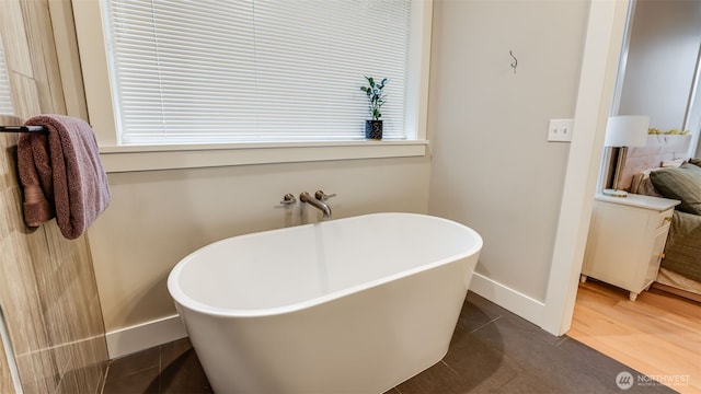 full bath with connected bathroom, baseboards, and a freestanding bath