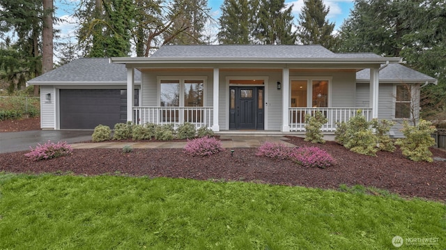 ranch-style house with a porch, a shingled roof, an attached garage, and aphalt driveway