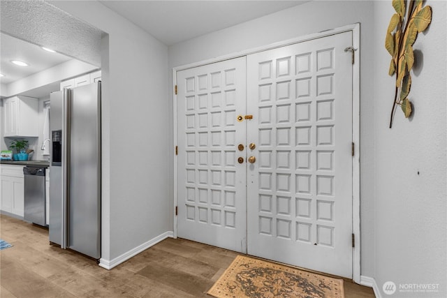 foyer entrance with recessed lighting, light wood-style flooring, and baseboards