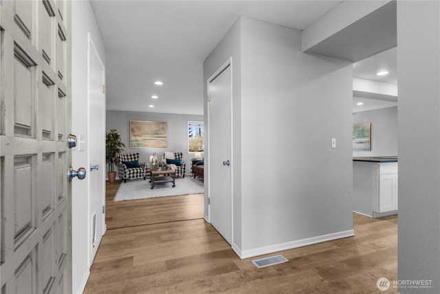 corridor with recessed lighting, visible vents, light wood-style flooring, and baseboards