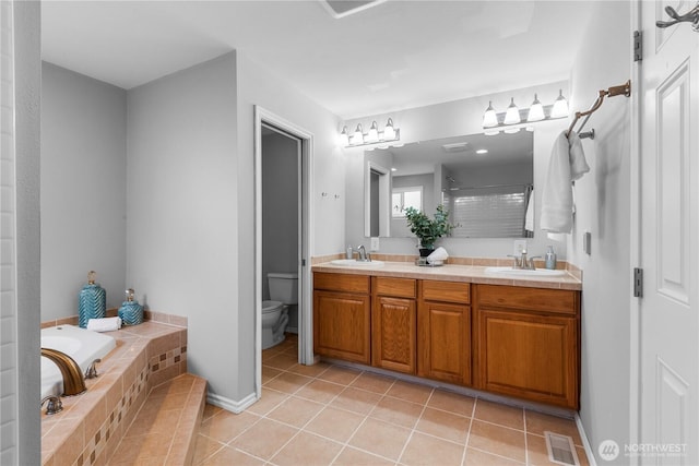 bathroom with tile patterned flooring, visible vents, a sink, and a garden tub