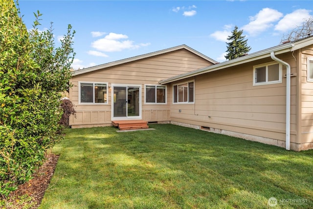 rear view of property with entry steps, crawl space, and a yard