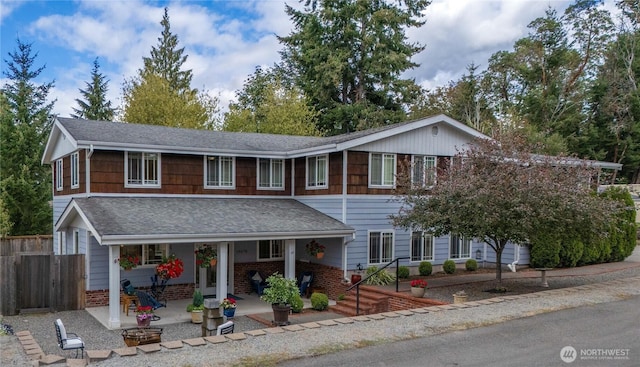 view of front of property with a patio, brick siding, roof with shingles, and fence