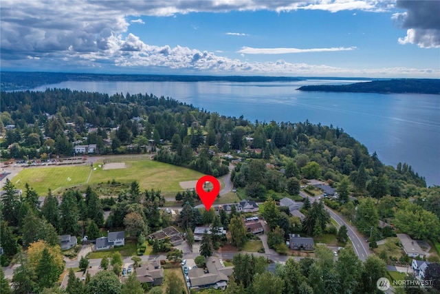 birds eye view of property with a water view and a wooded view