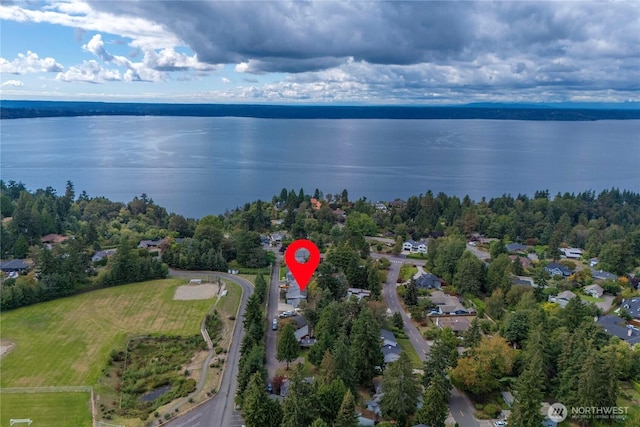 birds eye view of property with a water view and a wooded view