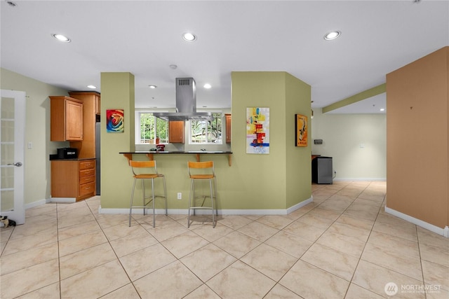 kitchen with dark countertops, light tile patterned floors, island range hood, and recessed lighting