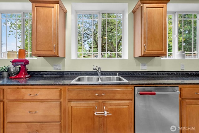 kitchen with a wealth of natural light, brown cabinets, dishwasher, and a sink