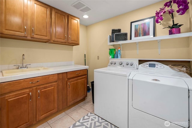 washroom with light tile patterned floors, a sink, visible vents, cabinet space, and washer and clothes dryer