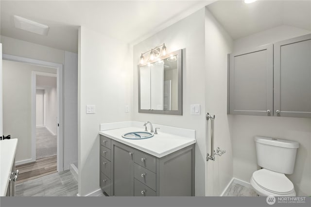 bathroom featuring toilet, baseboards, and vanity