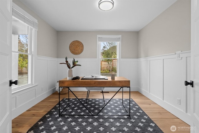 office with wainscoting, a decorative wall, and light wood-style flooring