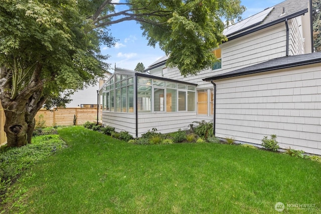 view of side of property with a lawn, fence, and a sunroom