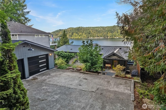 view of front of house featuring metal roof, a water view, and a view of trees