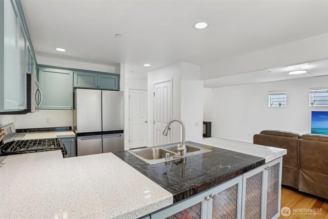 kitchen featuring open floor plan, recessed lighting, stainless steel appliances, and a sink