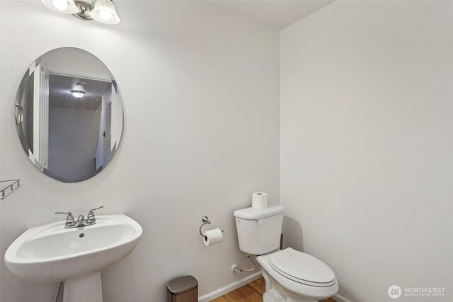 bathroom with a sink, baseboards, toilet, and wood finished floors