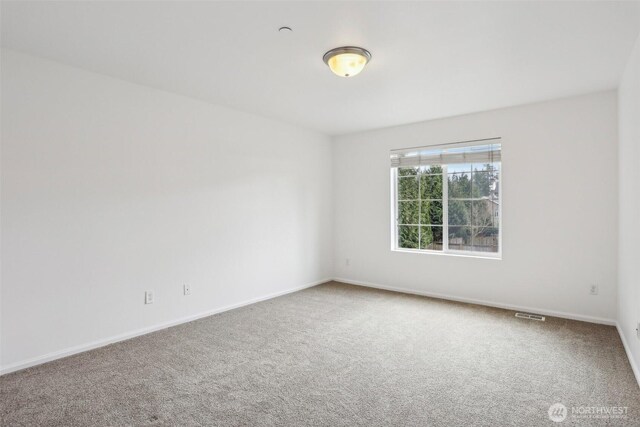 carpeted spare room with visible vents and baseboards