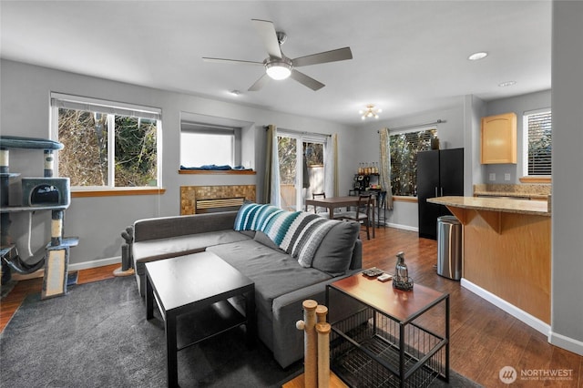 living room featuring dark wood-style floors, a fireplace, baseboards, and ceiling fan