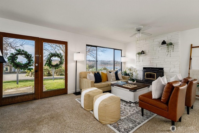 carpeted living area featuring ceiling fan and a stone fireplace