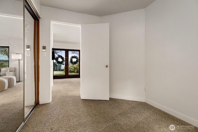 carpeted spare room featuring french doors, a healthy amount of sunlight, and baseboards