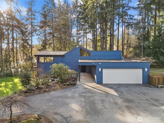 mid-century inspired home with metal roof, a standing seam roof, and driveway