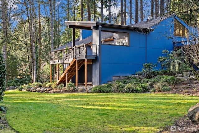 exterior space with a deck, stairway, metal roof, and a lawn