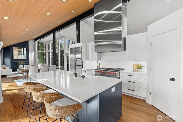 kitchen with lofted ceiling with beams, hardwood / wood-style flooring, a sink, backsplash, and high end appliances