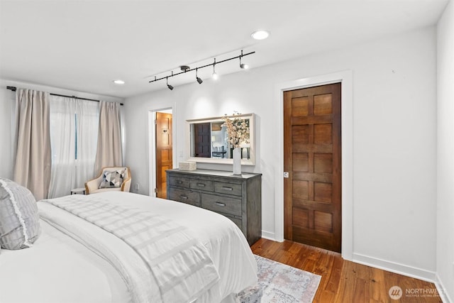 bedroom with recessed lighting, rail lighting, baseboards, and wood finished floors