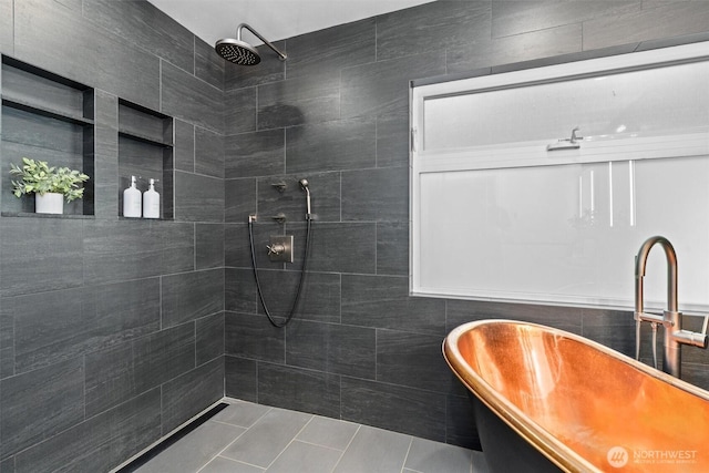 full bathroom featuring tile patterned floors, a sink, a tile shower, a freestanding bath, and tile walls