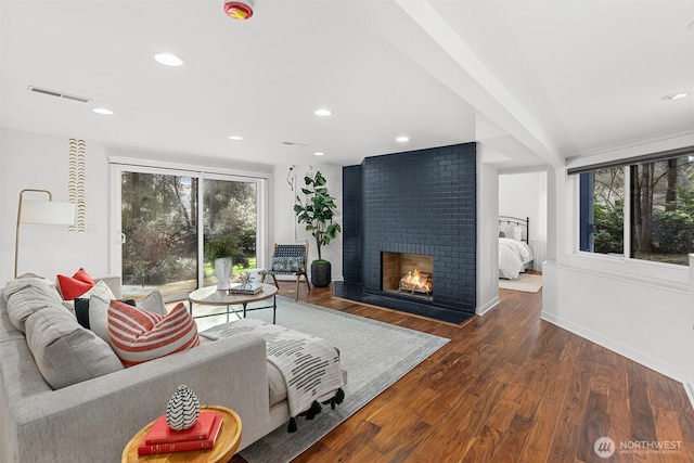 living area featuring a fireplace, plenty of natural light, wood finished floors, and visible vents