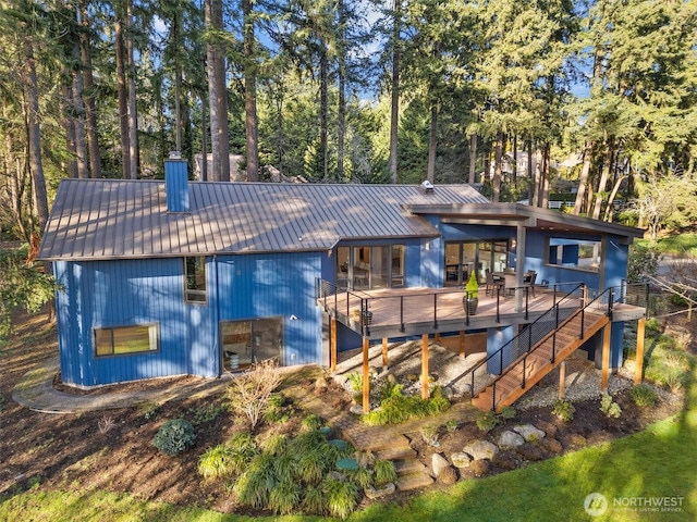 rear view of house featuring metal roof, stairway, a chimney, and a wooden deck
