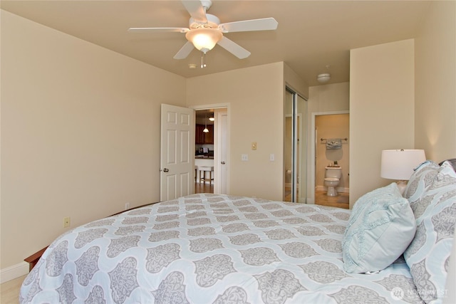 bedroom featuring a closet, ensuite bath, a ceiling fan, and baseboards