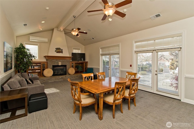 dining room featuring light carpet, visible vents, lofted ceiling with beams, an AC wall unit, and a stone fireplace