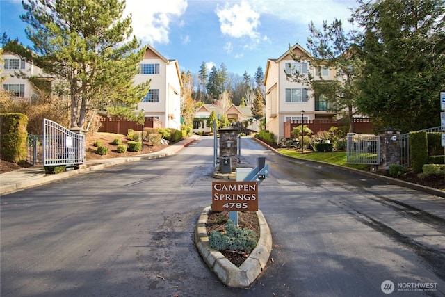 view of street with a residential view, curbs, and a gated entry