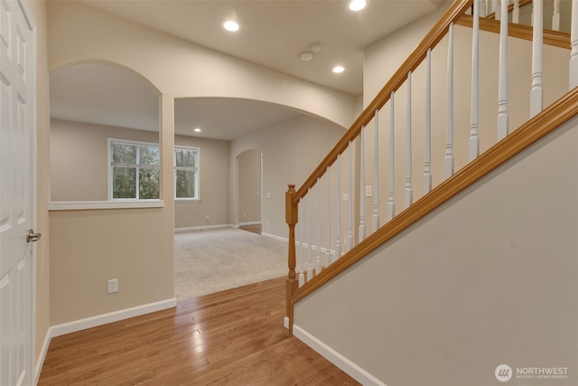 foyer entrance with arched walkways, recessed lighting, wood finished floors, baseboards, and stairway