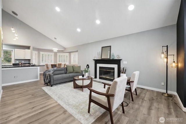 living room with baseboards, a fireplace with flush hearth, light wood-style flooring, high vaulted ceiling, and recessed lighting