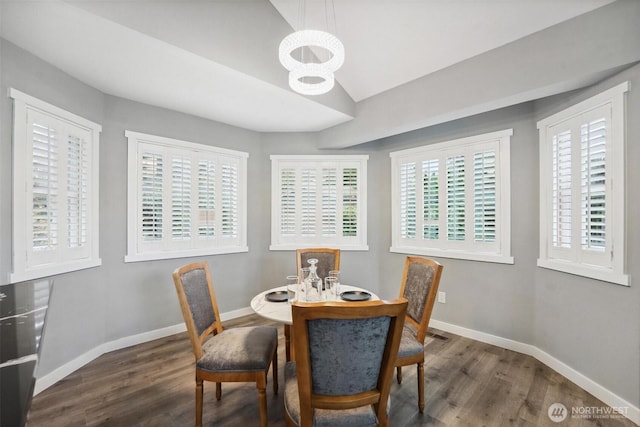 dining room with a notable chandelier, baseboards, vaulted ceiling, and wood finished floors