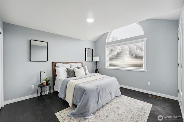 bedroom with lofted ceiling, wood finished floors, visible vents, and baseboards