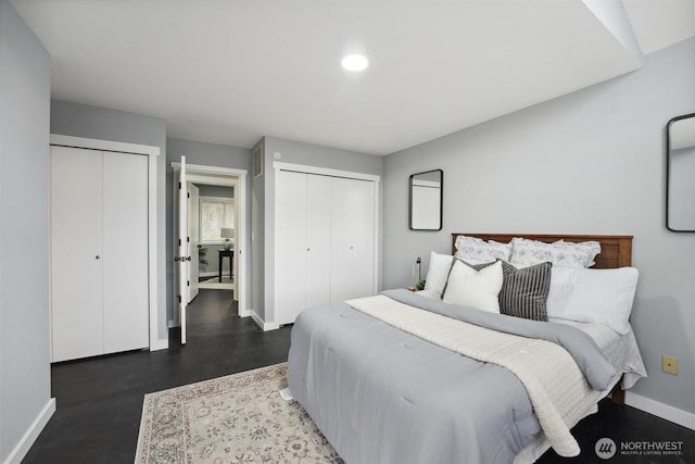 bedroom featuring multiple closets, baseboards, and wood finished floors