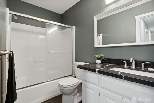 bathroom featuring combined bath / shower with glass door, vanity, and toilet