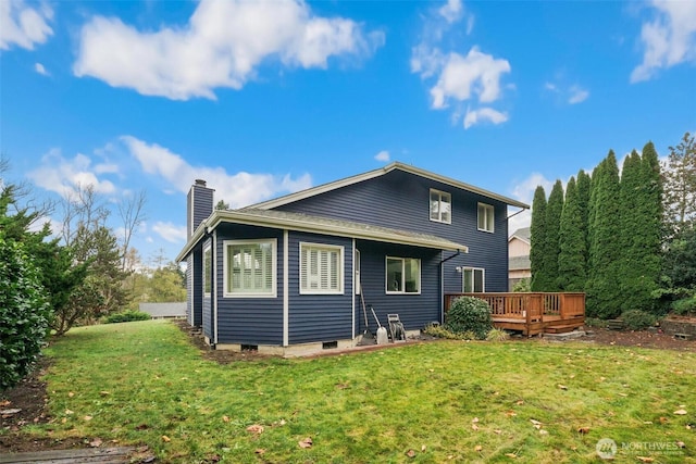 rear view of house featuring a lawn, a chimney, and a wooden deck