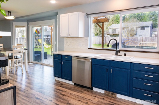 kitchen featuring blue cabinets, a sink, light countertops, decorative backsplash, and dishwasher