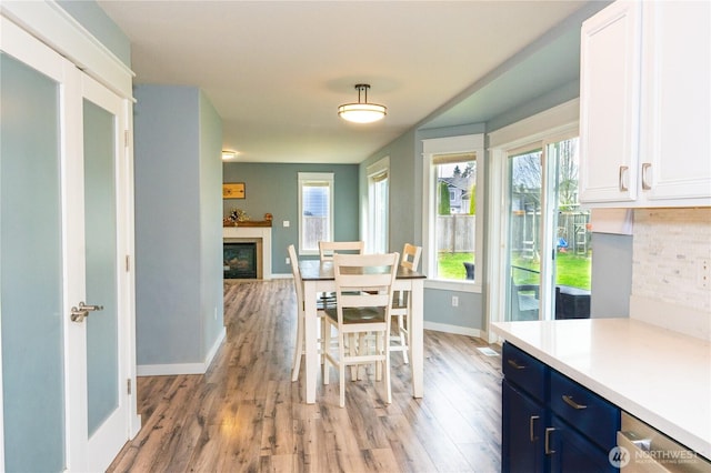 dining space with baseboards, a fireplace, and light wood finished floors