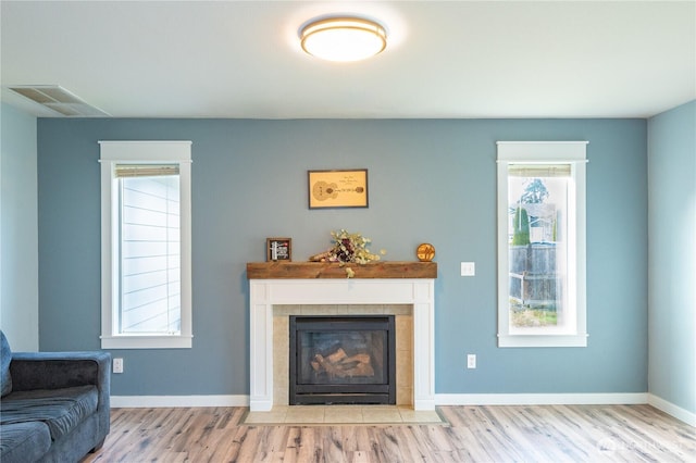 living area with visible vents, a tile fireplace, baseboards, and wood finished floors