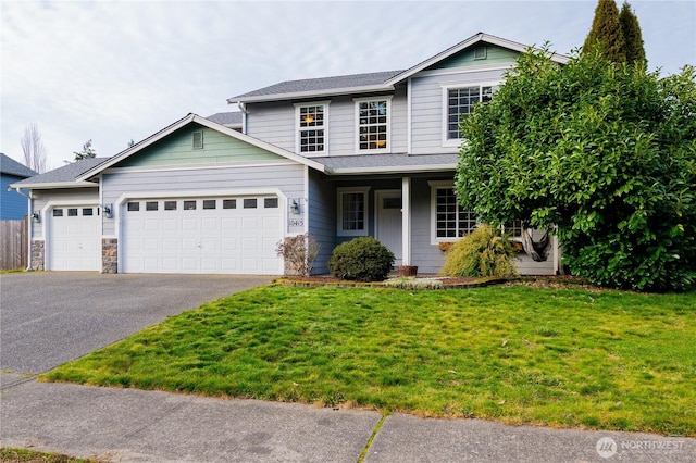 traditional-style house with aphalt driveway, a garage, a front lawn, and a shingled roof