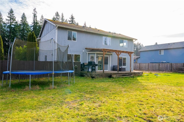 back of house with a lawn, a pergola, a trampoline, a fenced backyard, and a wooden deck