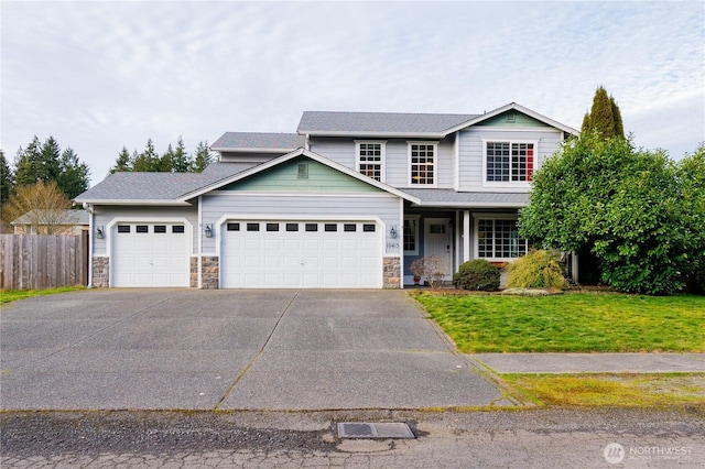 traditional home with driveway, stone siding, fence, a front yard, and an attached garage