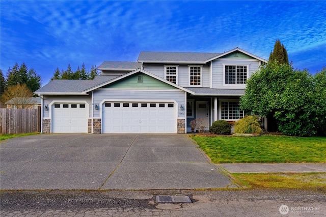 traditional-style house with a front lawn, stone siding, fence, concrete driveway, and a garage