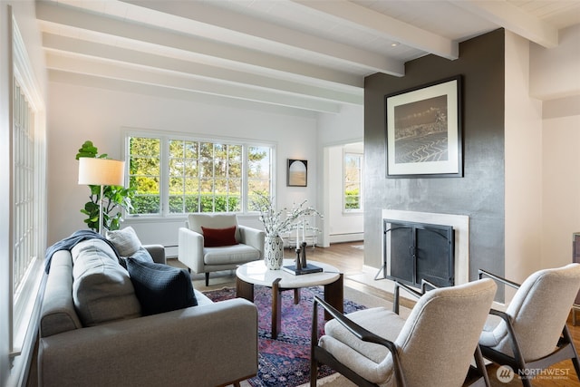 living room featuring beamed ceiling, wood finished floors, a baseboard heating unit, and a premium fireplace