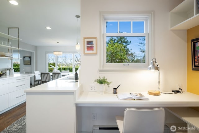 kitchen featuring a sink, white cabinetry, light countertops, dark wood-style flooring, and built in study area