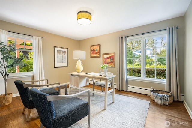 home office with a baseboard heating unit, plenty of natural light, baseboards, and wood finished floors