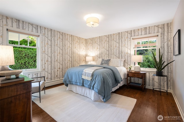 bedroom featuring baseboards, baseboard heating, wood finished floors, and wallpapered walls